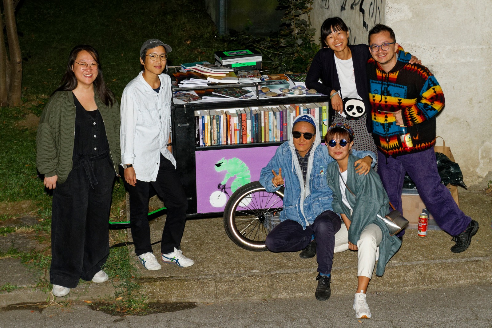 Das mobile Wandapanda & Tiger Archiv umringt von dem Projekt Team (Shi Yin, Noo Poravee, Pete Prison IV, Jameli Qairli, Weina Zhao) und Frederik Marroquín am Abend nach der Station in der Semmelweisklinik. Alle grinsen in die Kamera.