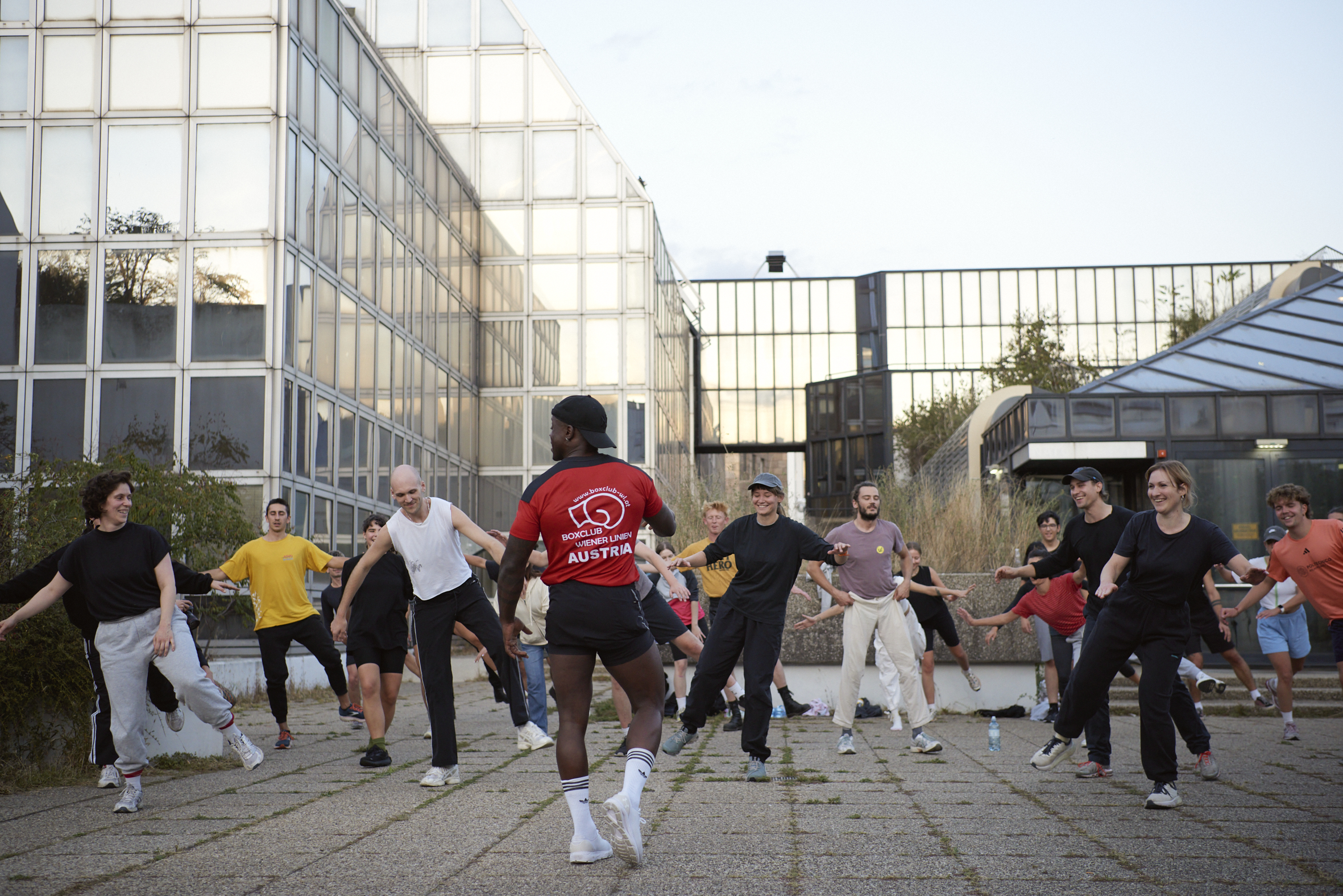 Gruppe von Festivalbesucher:innen beim Schattenboxen im öffentlichen Raum auf dem Areal der ehemaligen WU im 9. Bezirk. Dabei wurden Blicke und Körper für die sozialen und sportlichen Potenziale des urbanen Raums sensibilisiert.