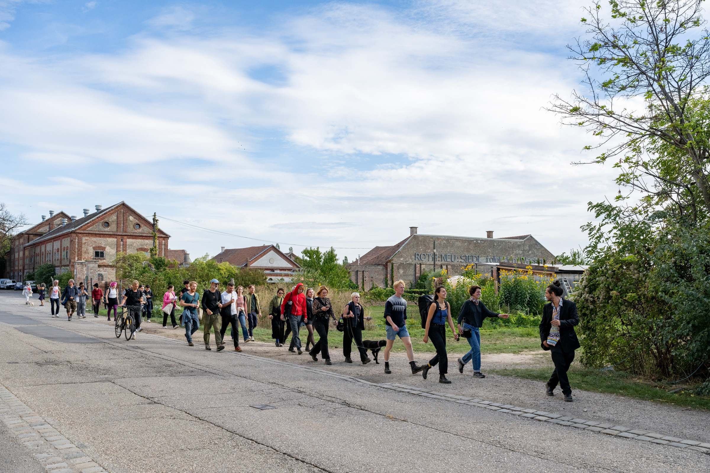 Menschengruppe von etwa 30 Personen unterwegs vom Zukunftshof am Stadtrand ins Zentrum entlang der künstlerisch-urbanen Performance-Reise »Touch Ground« von Theresa Schütz