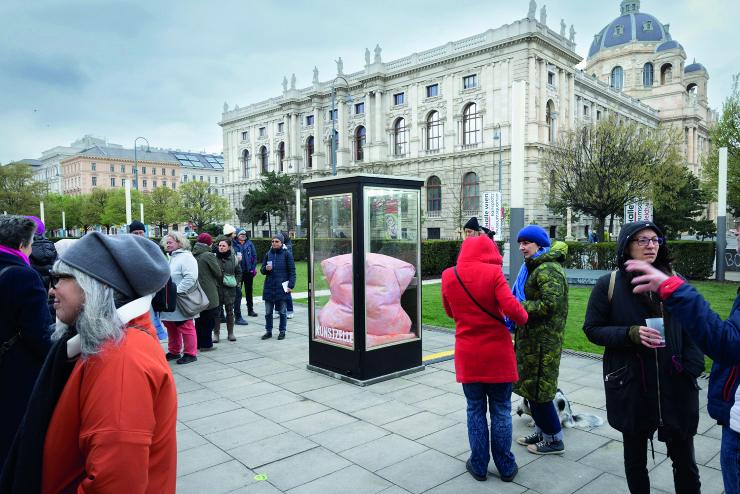 Skulptur im öffentlichen Raum, Menschen stehen um diese herum und sprechen miteinander.