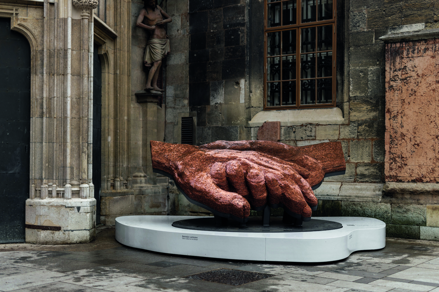 Bild der fertiggestellten Skulptur, zwei ineinander verschränkte Hände aus 1-Cent-Münzen, vor dem Wiener Stephansdom