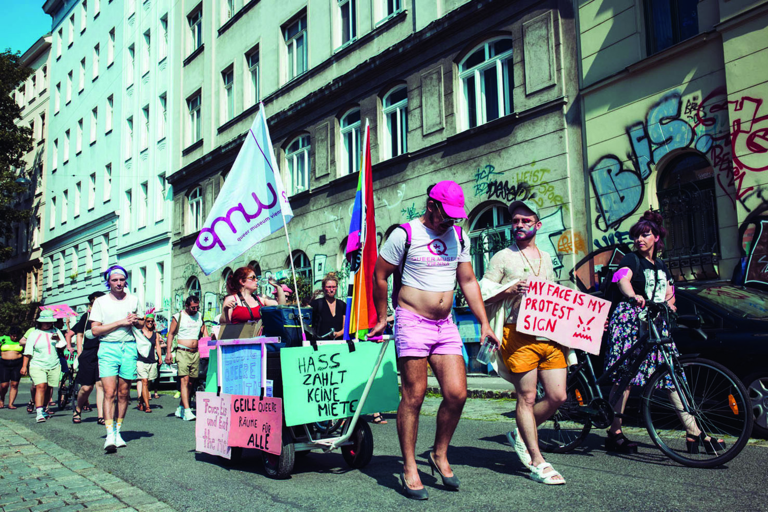 Bild einer queeren Demonstrationen mit Plakaten, Fahnen und Spruchtafeln