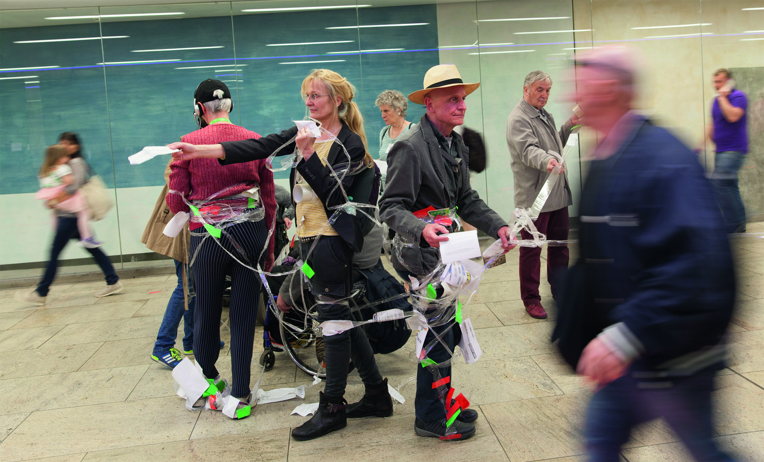 Foto der Aktion, Personen mit Zetteln an Fäden im öffentlichen Raum (U-Bahn-Station "Karlsplatz")