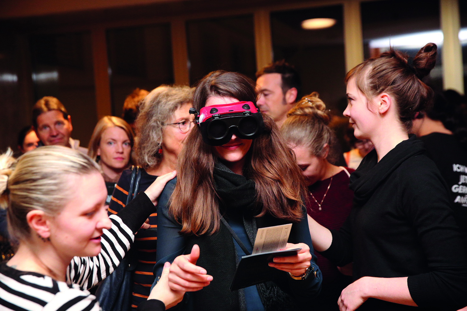 Foto einer Aufführung, junge Menschen in einem Raum, eine Person trägt eine VR-Brille