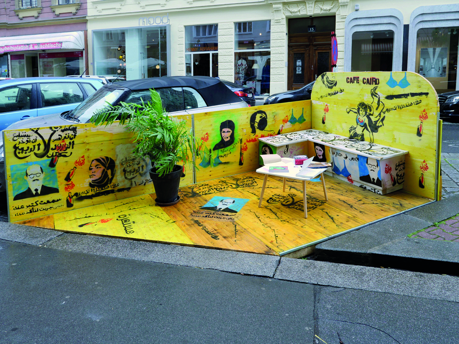 Foto des Café Cairo, eine gelbe Banknische auf einem innerstädtischen Parkplatz