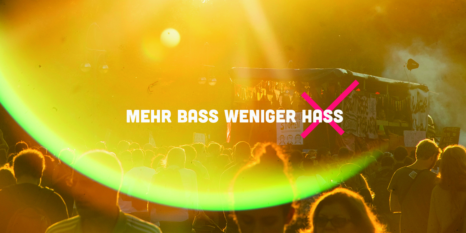 Eine in leuchtendes Gelborange getauchte Konzert-/Rave-Situation, darüber der Text "Mehr Bass weniger Hass"