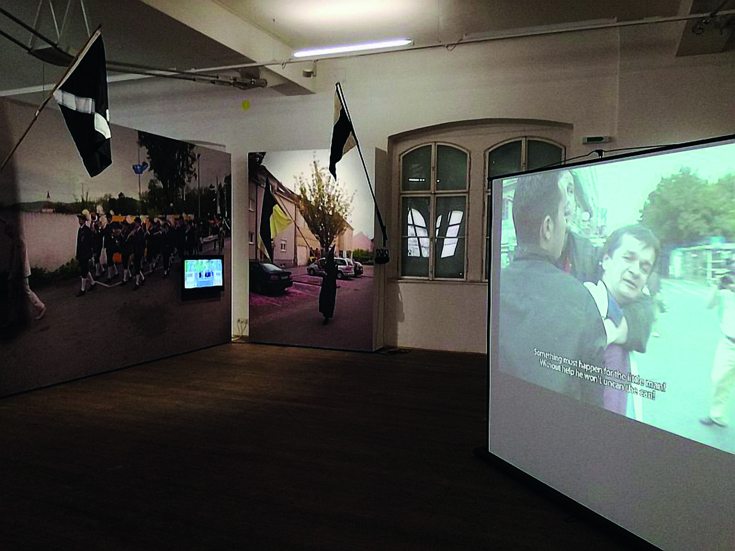 Ausstellungsraum, rechts eine große Videoinstallation, links und hinten großflächige Fotografien