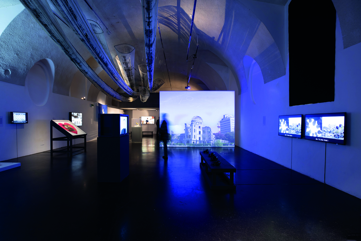 Ausstellung im Q21/MQ Wien, blaues Licht, mehrere Monitore mit Videoeinspielungen in unterschiedlichen Größen und Präsentationsformen