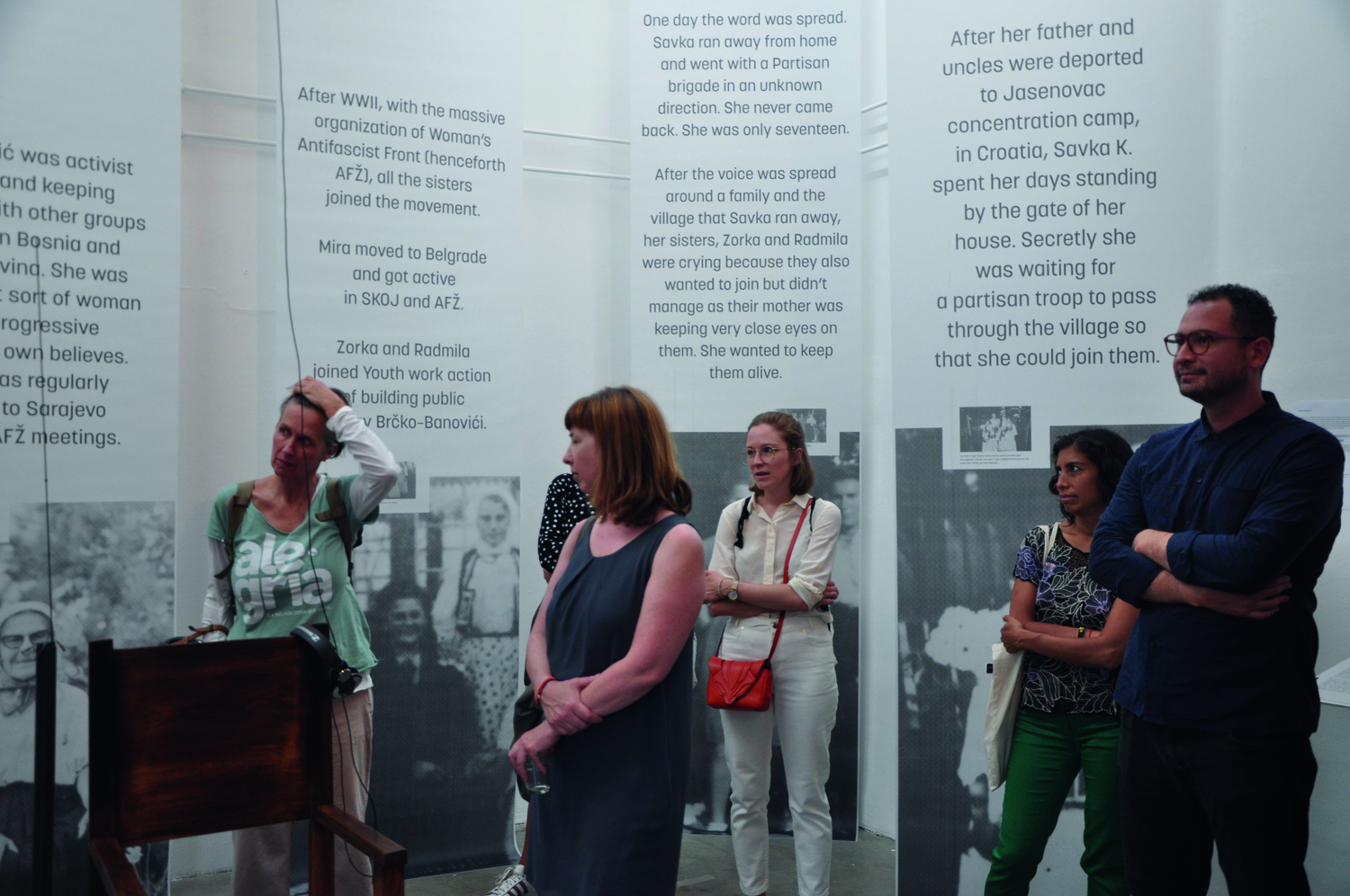 Ausstellungsraum mit Schrift-Text-Bannern an den Wänden, mehrere Personen stehen davor im Raum