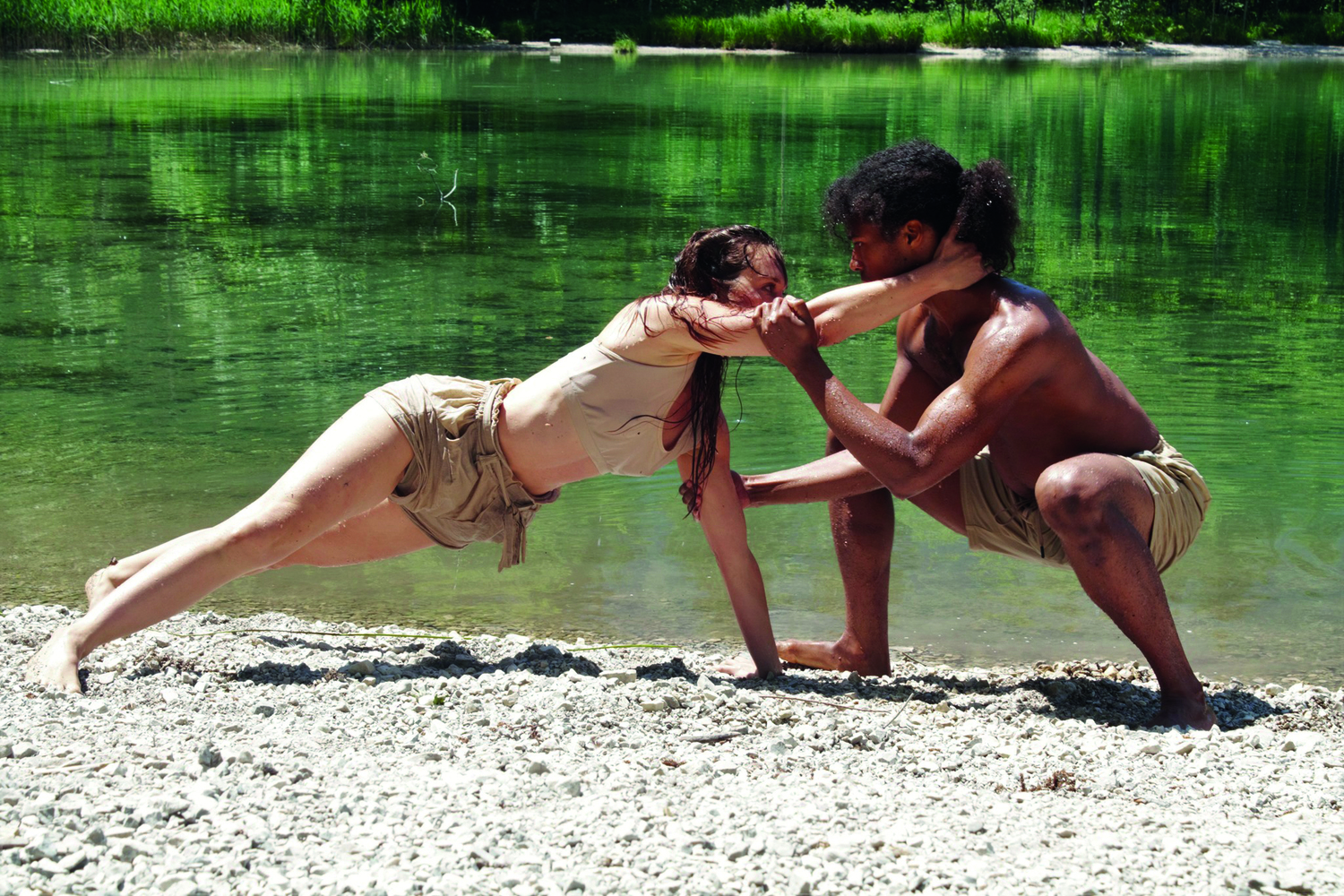 Foto während des Filmdrehs zu "Liebes:Leben", zwei am Boden performende Personen an einem Ufer