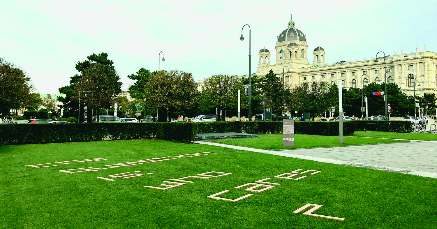 Wiese auf dem Wiener Maria-Theresien-Platz, in die Wiese ist ein Text hineingeschnitten