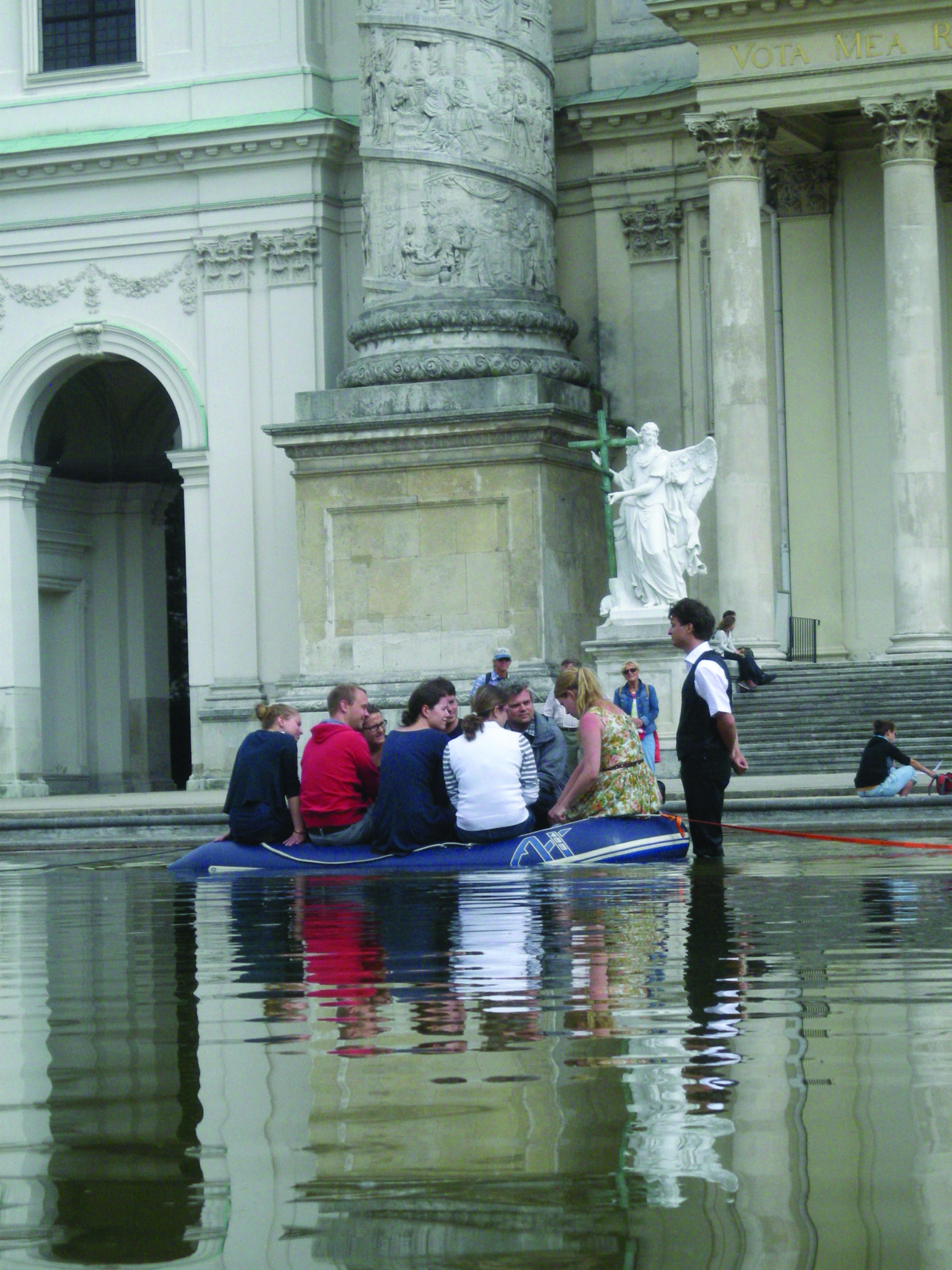 Personen einem Schlauchboot auf dem Teich vor der Wiener Karlskirche