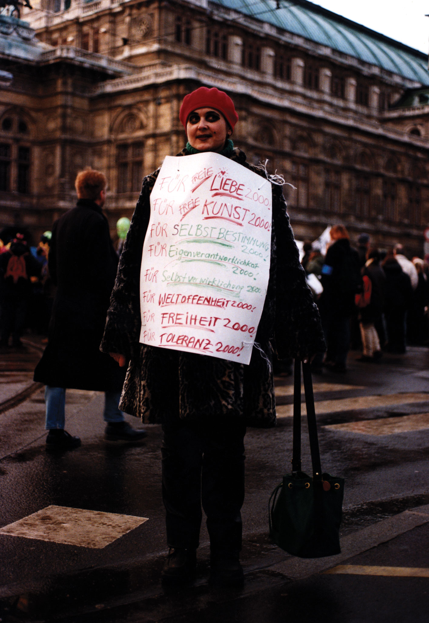 Christa Biedermann mit einem Plakat um ihren Körper steht vor der Wiener Staatsoper